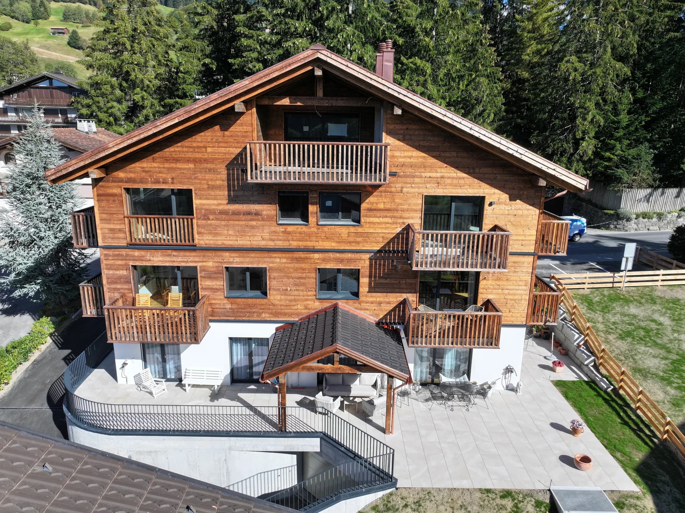 Das fertige MFH Malein mit gebrannter Holzfassade und Terrasse im Erdgeschoss